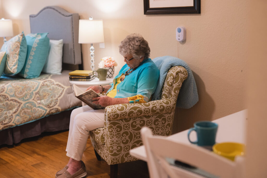 Senior woman sitting in bedroom chair reading